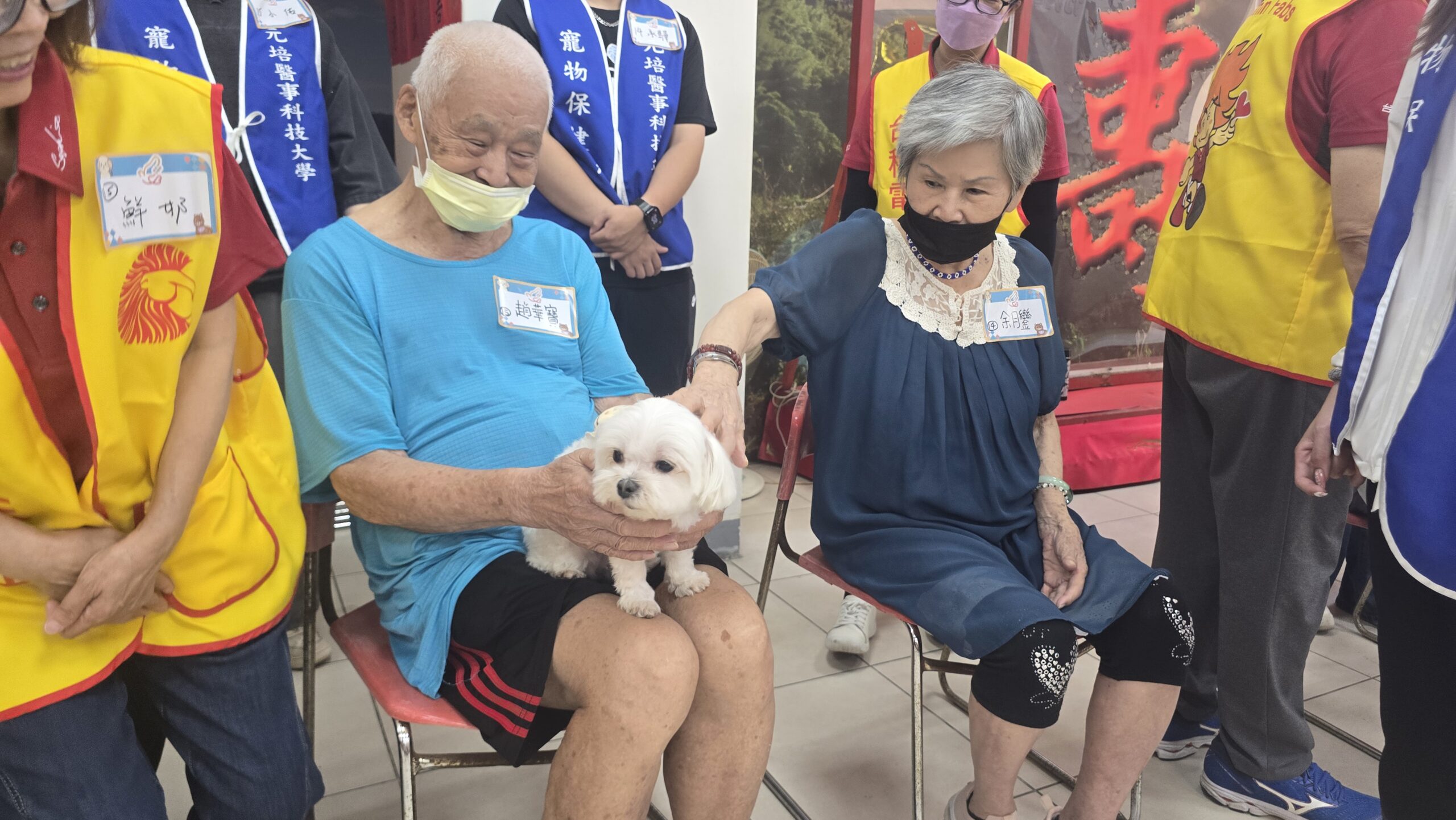 圖/長輩在志工與學生的陪伴下,親手餵食心輔犬,透過手部動作訓練精細肌肉控制,也從照顧毛小孩的過程中獲得成就感與自信心。(台積電慈善基金會 提供)