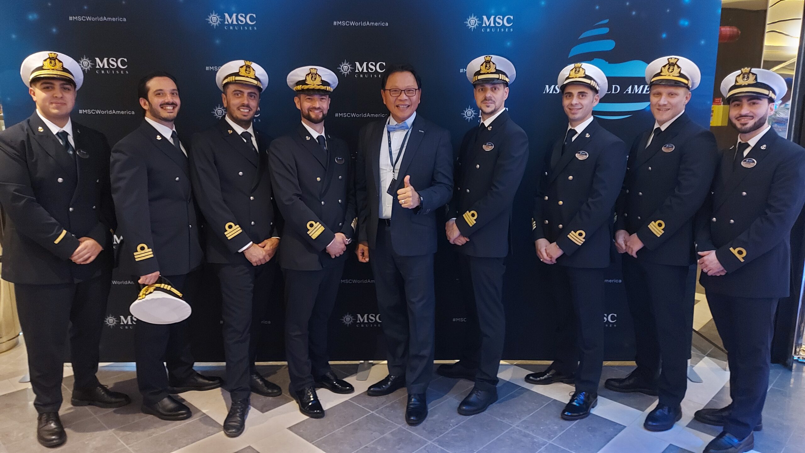 劉奕樑登上MSC亞美利加號，與船上船員於活動背板前合影(圖/劉奕樑)